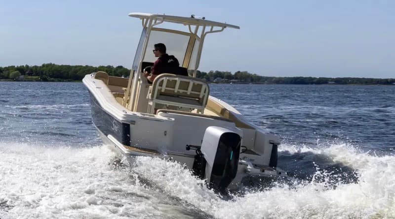 Electric Scout 215 XSF center-console boat speeding across open water, viewed from the stern with white wake and an outboard motor.