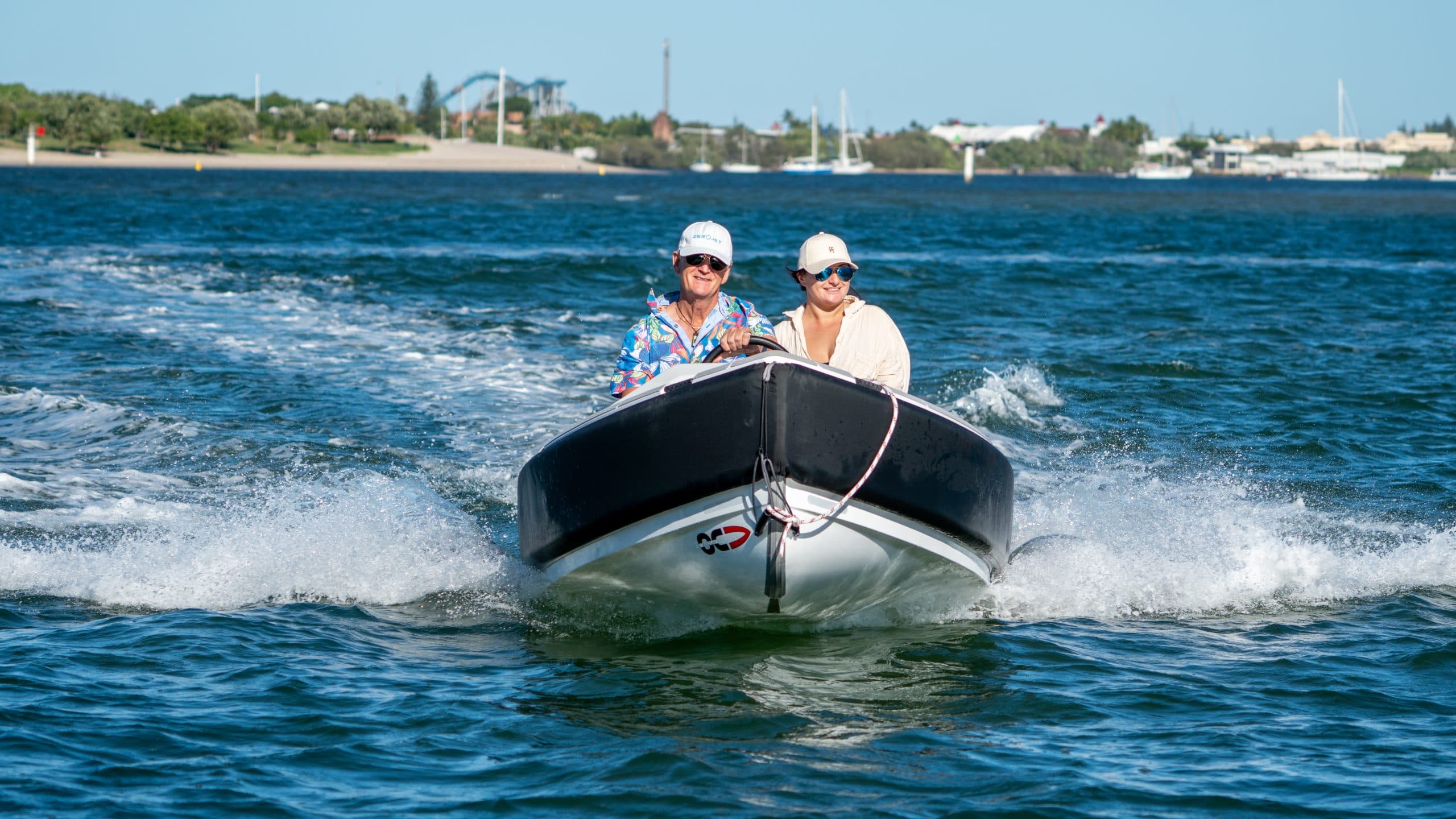 Two people in a white tender with black rub rail heading towards the camera.